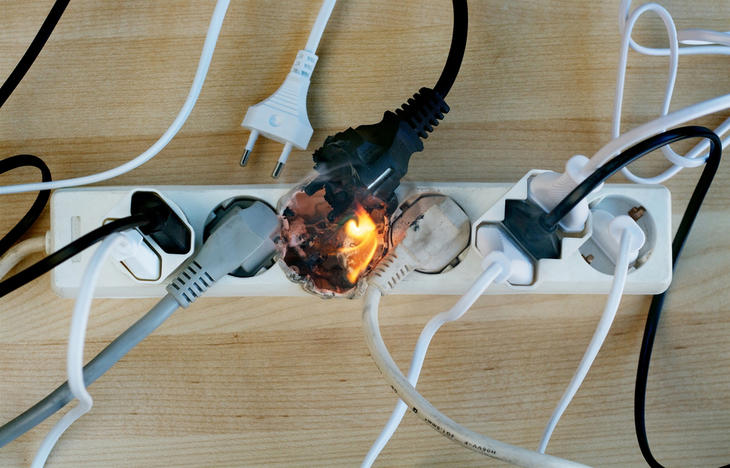 Liten flamme fra en ledning koblet til et strømuttak med mange ledninger.