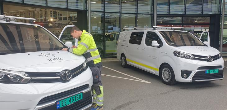 To nye hvite elektriske varebiler står utenfor salgslokaler på Forus. En montør i gul jakke står ved den ene bilen. 