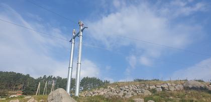 Ny strømmast i Hjelmeland er satt opp og montør jobber i toppen for å feste line 