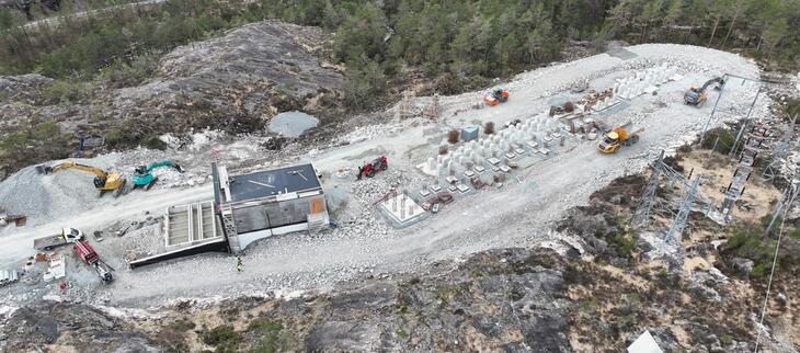 Foto av nytt anlegg under bygging tatt fra drone. Kontrollhus til venstre og fundament for utendørsanlegg til høyre i bildet. 